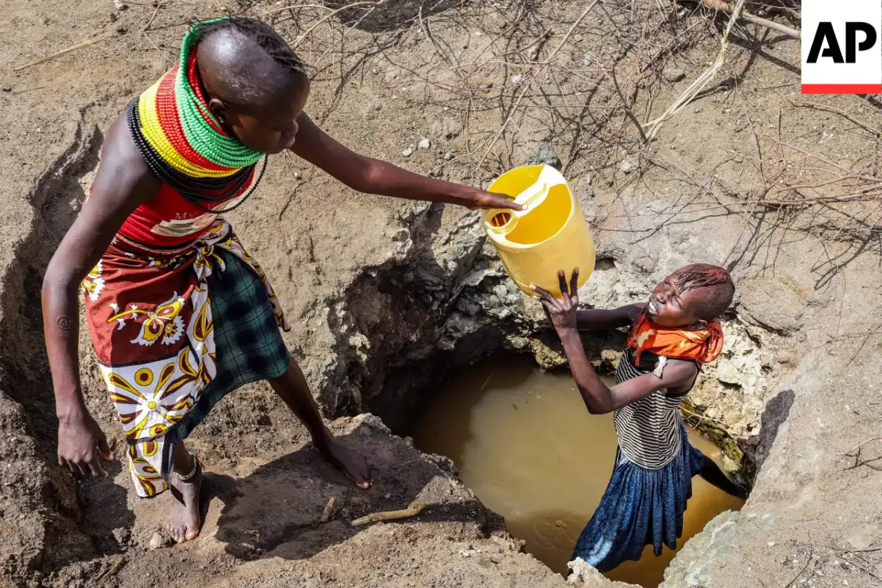 Turkana women passing a jerrycan up from a hand-dug water pit in drought