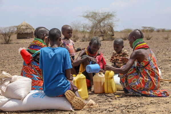 World Food Programme sacks beside Turkana women filling jerrycans with scarce water