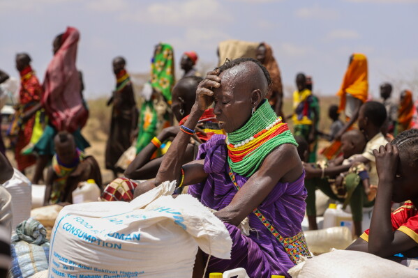 Turkana woman beside food aid sacks marked for human consumption during drought relief